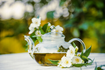 Fototapeta na wymiar Philadelphus or garden jasmine flowers, healthy herbal tea cup of hot tea. Romantic dinner with therapeutic fragrant tea.