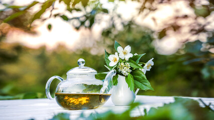 Obraz na płótnie Canvas Philadelphus or garden jasmine flowers, healthy herbal tea cup of hot tea. Romantic dinner with therapeutic fragrant tea.