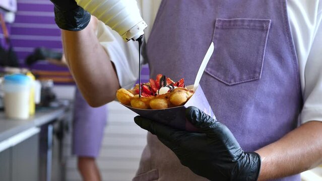 The cook pours chocolate over a Hong Kong bubble waffle with ice cream.