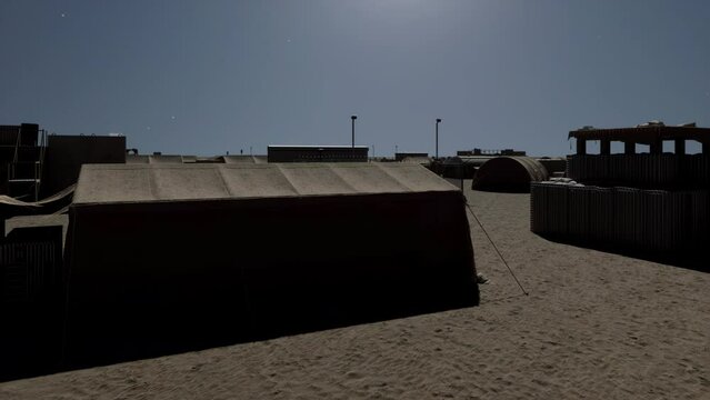 An abandoned and deserted military base and army training camp in the middle of the desert as viewed under the moonlight on a bright starry night.