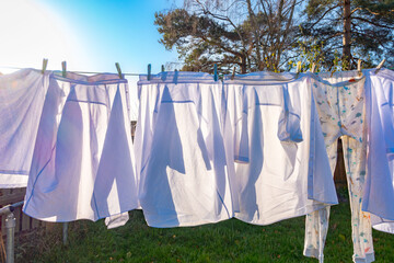 White shirts and clothes drying outside on a washing line with a blue sky on a clear, sunny autumn day.