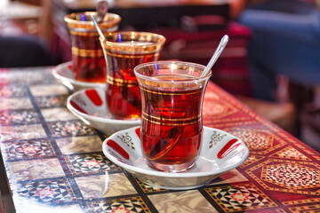 three tea glasses of traditional turkish tea and spoon on backgammon table	