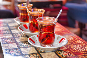 three tea glasses of traditional turkish tea and spoon on backgammon table	