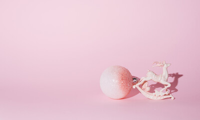 New Year's decorations on a pastel pink background. Reindeer and a big ball of white and pink...