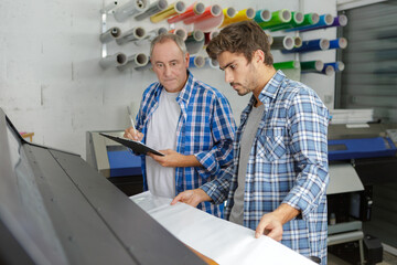 Naklejka na ściany i meble two men looking down at professional printer