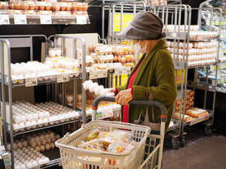 スーパーのたまご売り場で買い物する高齢日本人女性