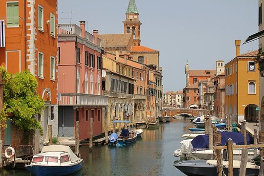 water canal with medieval bridges, Italian town of Chioggia on the Venetian lagoon, colorful houses, moored boats, stone bridges, typical oriental-Venetian windows