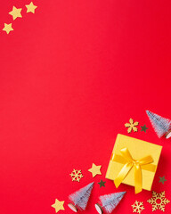 Christmas border with golden gift box with mini Christmas trees and baubles on bright red background