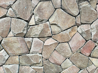 Granite stone wall surface. These stones have been joined together using mortar. The construction...