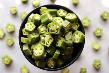 Bhindi fry. Farm fresh raw okra slices in a wooden bowl. Close up of chopped Lady Fingers or Okra. Copy space. Cut vegetables. Green healthy veg.