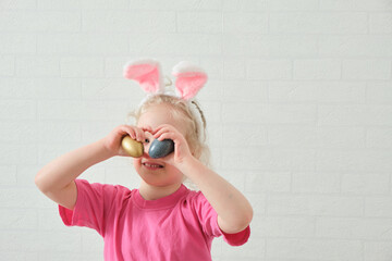 little girl in bunny ears , Easter concept, table with Easter eggs, celebrating Easter.