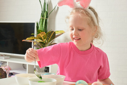 little girl in bunny ears , Easter concept, table with Easter eggs, celebrating Easter.