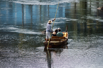 Boatman in a striped shirt walking with a couple of tourists