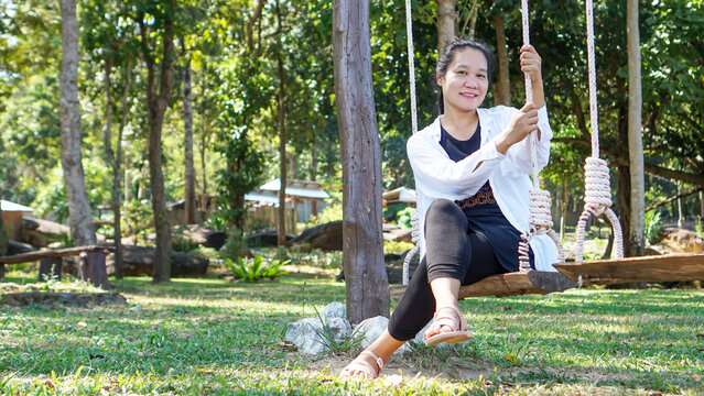 Asian woman sitting on a swing in the countryside relaxing