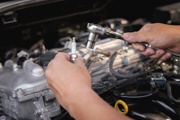 Technician holding gasoline engine spark plug in hand and a wrench to disassemble and maintain in the garage.service cycle of engine maintenance fix problems caused by abnormal operation of engine