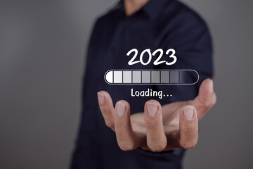 Man hand holding taps a virtual download bar. 2023 Loading.