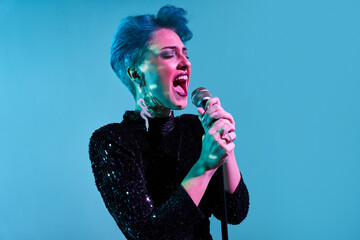Young woman with microphone singing in studio