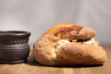 Ruddy poppy seed roll on a wooden table with a black clay cup and a blurred background