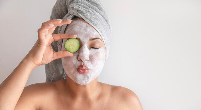 Young woman covering eye with cucumber slice
