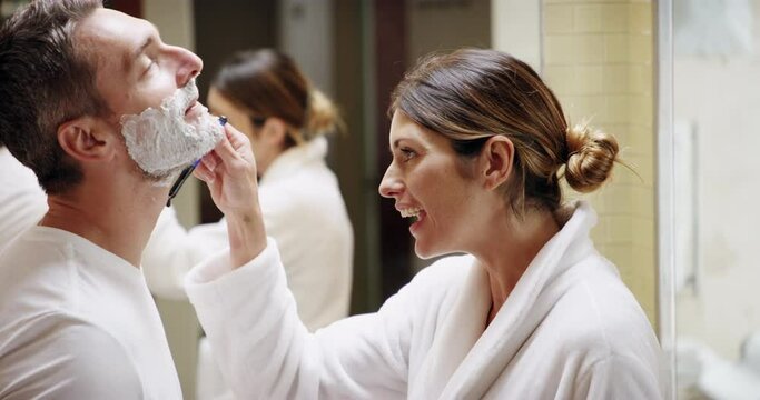 Woman, man and shave beard, facial cream and happy smile, razor and grooming in home bathroom together. Couple, happiness and wife helping husband, face hair and love with skincare in the morning