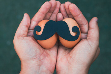 close up view of a fake paper mustache stick down on two eggs- man month november