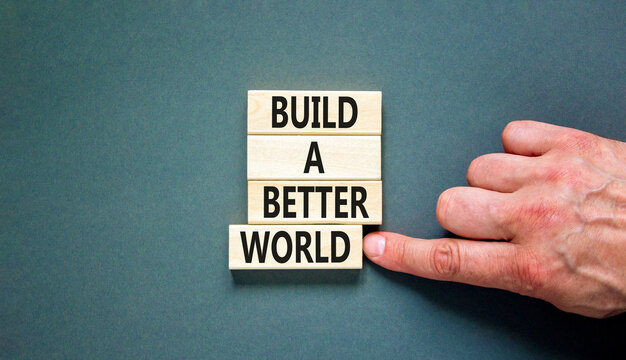 Build a better world symbol. Concept words Build a better world on wooden cubes. Beautiful grey table grey background. Businessman hand. Business build a better world concept. Copy space.