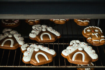 Christmas gingerbread house shaped cookies with white snow icing baking in the oven. Homemade festive traditional gingerbread men getting ready in a stove. Getting ready for Christmas Eve