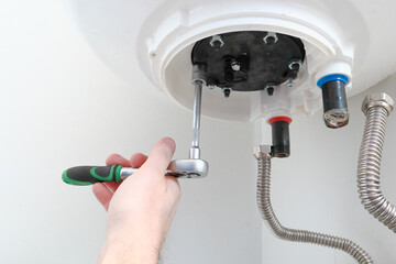 Repair and maintenance of boilers. Man's hand putting a new water heater in a boiler.