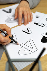A graphic designer develops a logo for a brand. The illustrator draws sketches on paper.
