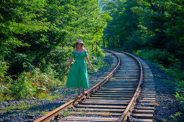 a woman in a green dress walks along the railway