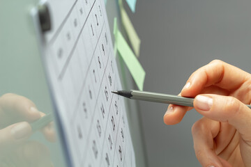 A woman's hand marks the planned day on the calendar with a pencil.