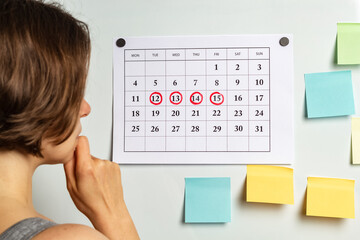 Thoughtful woman looks at the calendar with the menstrual period.