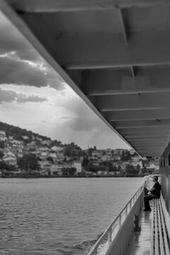 Black and white of water side passage of ferry boat on Marmara sea, with man sitting on a bench at the far end, Istanbul, Turkey
