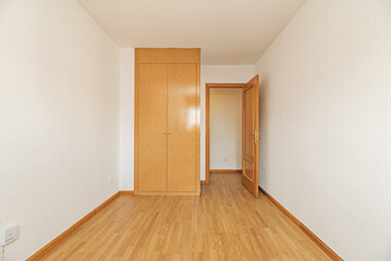 Empty room with oak colored wooden built-in wardrobe with matching flooring, access doors, wooden...