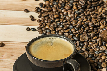 A freshly served coffee in a cup next to a quantity of beans ready for grinding