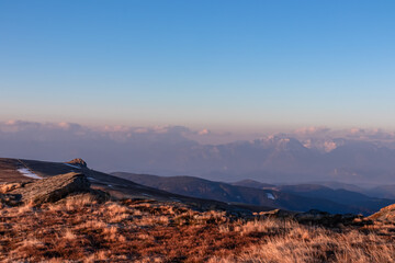 Scenic view of rock formation and Karawanks mountains at sunrise seen from alpine meadow at...