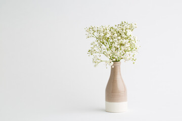 Small white flowers on a white background. Soft home decor. White flowers in a vase.