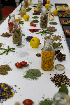 Spices and Herbs Finely Chopped with Lemons, Tomatoes and Olives on the White Table
