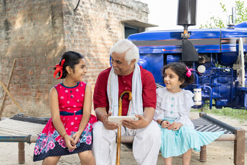 Rural grandfather with granddaughter using digital tablet at village home.