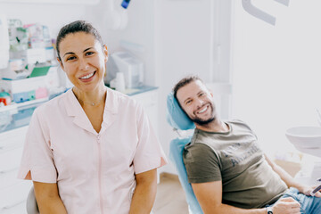 Happy dentist woman looking in camera with satisfied patient on shoulders