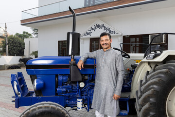 Farmer standing with Tractor at village home.