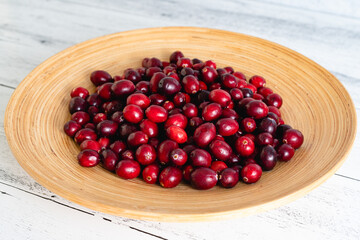 Ripe cranberries on wooden plate close-up