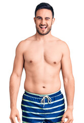 Fototapeta premium Young handsome man wearing swimwear winking looking at the camera with sexy expression, cheerful and happy face.