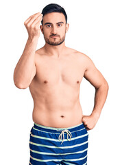 Young handsome man wearing swimwear doing italian gesture with hand and fingers confident expression