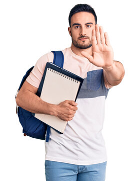 Young handsome man wearing student backpack and notebook with open hand doing stop sign with serious and confident expression, defense gesture