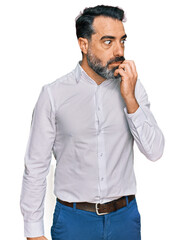 Fototapeta premium Middle aged man with beard wearing casual white shirt looking stressed and nervous with hands on mouth biting nails. anxiety problem.