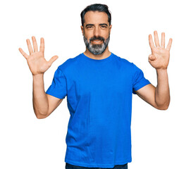 Fototapeta premium Middle aged man with beard wearing casual blue t shirt showing and pointing up with fingers number nine while smiling confident and happy.