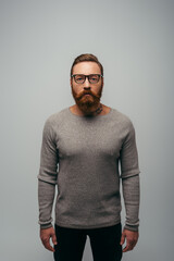 Obraz premium bearded and tattooed man in long sleeve and eyeglasses looking at camera isolated on grey.