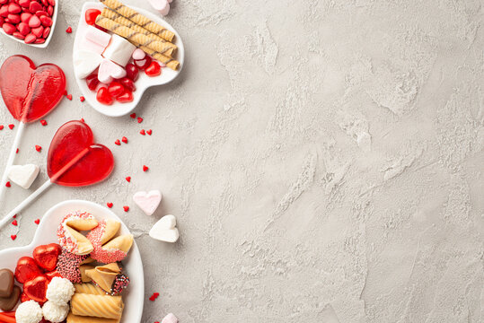 Valentine's Day celebration concept. Top view photo of heart shaped saucer with sweets cookies candies lollipops and confetti on concrete texture background with copyspace
