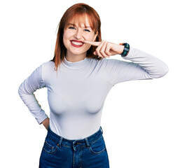 Redhead young woman wearing casual turtleneck sweater pointing with hand finger to face and nose, smiling cheerful. beauty concept